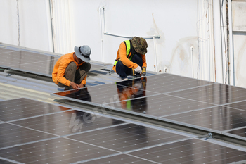 Technicians Install photovoltaic solar modules on roof of house.