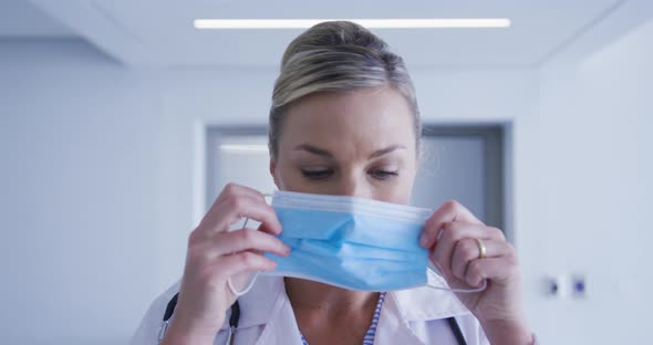 Portrait of caucasian female doctor putting face mask on