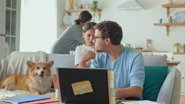 Social Distancing. A Busy Father Tries To Work Remotely with His Child and Wife at Home.