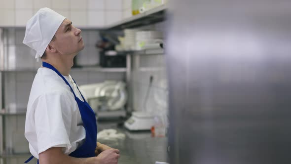 Side View Portrait Concentrated Caucasian Cook Choosing Additives in Commercial Kitchen Indoors