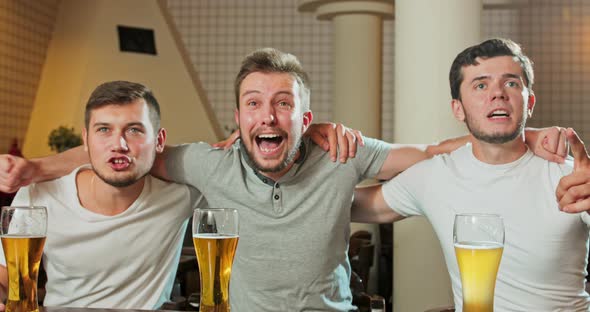 Cheerful Old Friends Having Fun Watching a Football Game on TV and Drinking Draft Beer