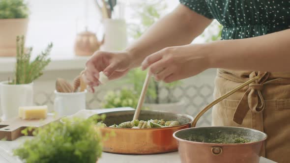 Crop woman adding mozzarella balls to pasta