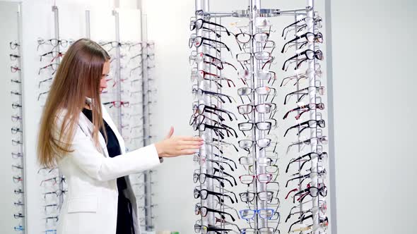 Choice of glasses in the store. Beautiful young woman choosing stylish eyeglasses in the optical sho