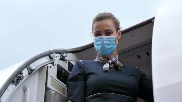 Flight Attendant with Coronavirus Protection Mask Closes Aircraft Door