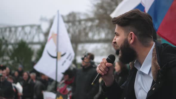 Protester Speaker with Microphone Gives Speech to Rally Crowd with Russian Flags