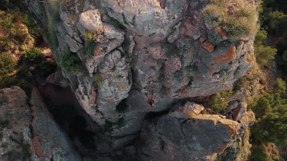 Climbing sportswoman rappelling in the mountain. Drone view of climber young fit girl descending.
