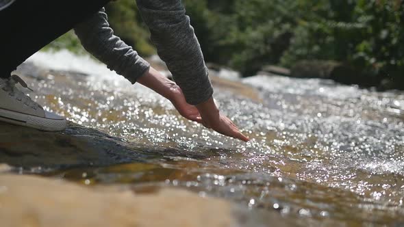 Young Female Hiker Washes Her Hands in Clear Water of Mountain River. Unrecognizable Woman Refreshes