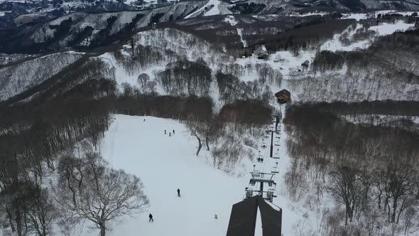aerial of people skiing down white mountain ski resort slopes near a lift in Nozawa Onsen Japan