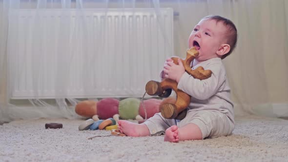 A small child is crying sitting on the carpet in the nursery. Toddler baby boy is naughty