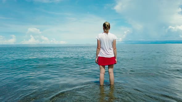 A Woman Is Standing in the Sea Against the Blue Sky