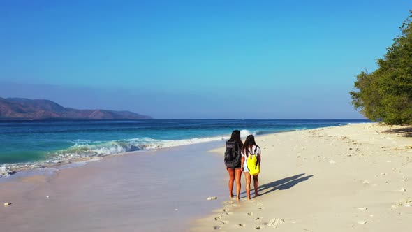 Girls enjoying life on beautiful bay beach holiday by shallow ocean with white sandy background of G