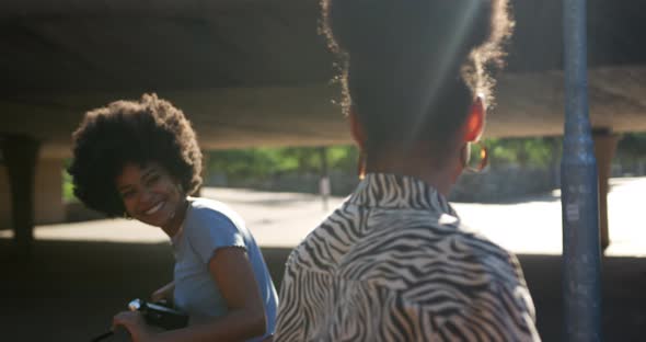 Two mixed race women laughing under bridge