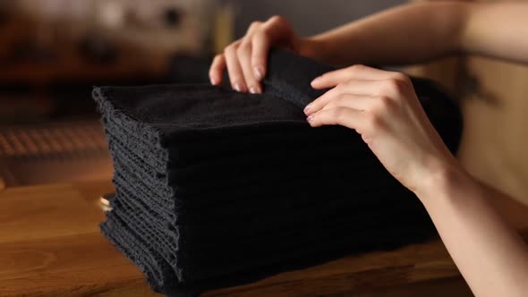 housewife woman touch a stack of fresh washed clean linen with her hands. black towels. homework.