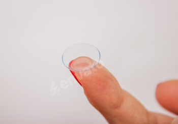 Female finger with contact lens isolated on white