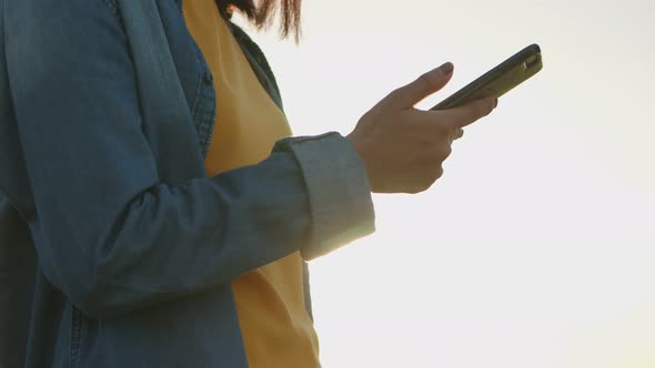 Asian woman scrolls through social media feed on a smartphone.