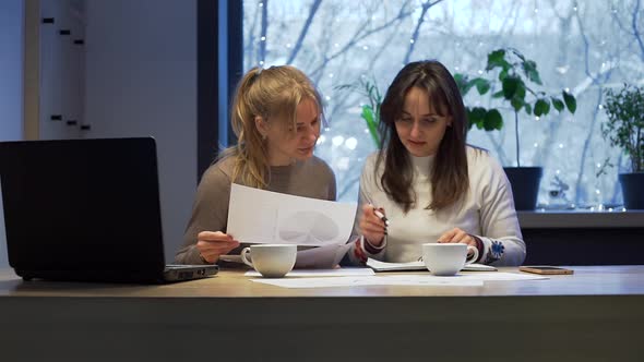 Women Doing Paperwork Together Late at Evening