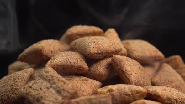 Hot crispy chocolate pads with smoke rotate on a black background. Cocoa cereal dessert