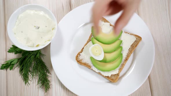 Woman Preparing a Healthy Breakfast - Toast with Curd Cheese and Avocado, Quail Eggs