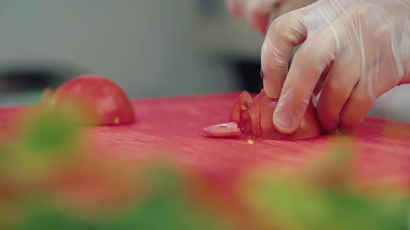 Cook Cuts a Fresh Tomato for a Salad with a Knife