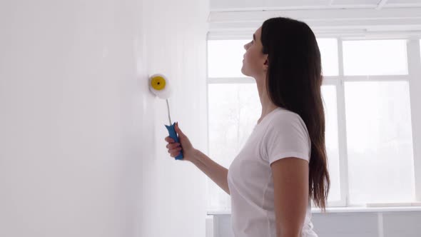 Young Lady Making Home Renovation Painting Wall with Painter and White Dye