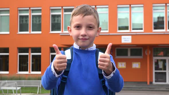 A Young Boy Smiles and Shows a Double Thumb Up To the Camera - an Elementary School