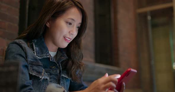 Woman use of mobile phone at night in coffee shop