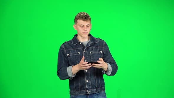 Smiling Male Goes and Takes a Selfie with Smartphone on Green Screen at Studio. Slow Motion