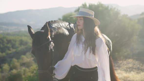 Side View of Confident Horsewoman in Straw Hat and Graceful Animal Walking in Sunrays in Summer