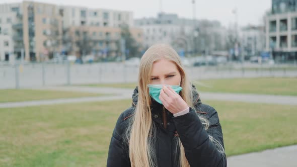 Female Putting a Medical Mask on Her Face on the Street