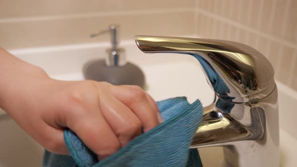 Woman Rubs Faucet with Blue Cloth, Hand Closeup.