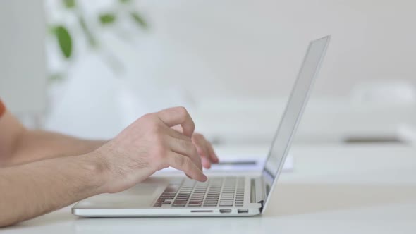 Side View of Young Man Typing on Laptop Keyboard