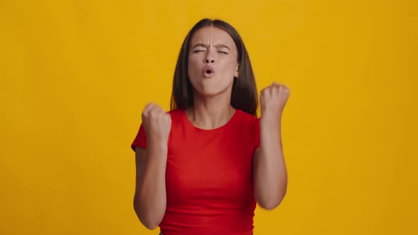 Female Shouting And Shaking Fists In Joy Over Yellow Background