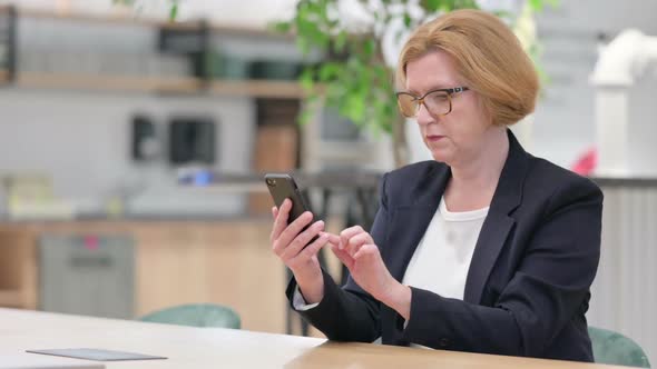 Serious Businesswoman Using Smartphone in Office