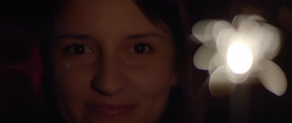 Close up of a woman opening her eyes and smiling, with sparkles in front of her