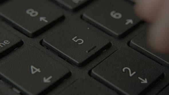 The Finger Presses a Button with a Number on the Keyboard