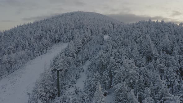 Abandonded ski lift at the peak of a snow covered mountain SLOW AERIAL SLIDE