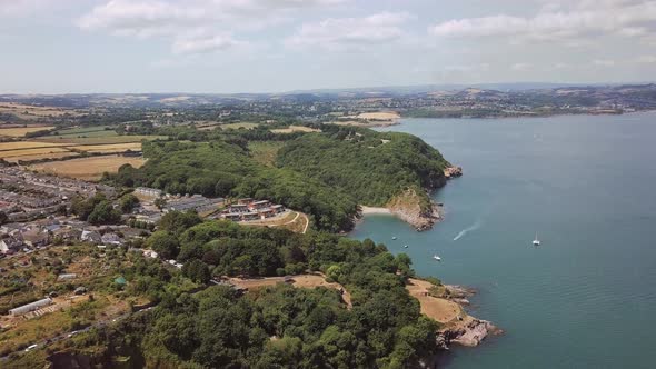 Aerial view of Brixham beach and town. Boats are docked in the water, cliffs are visible in the dist