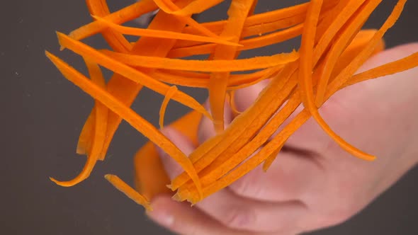 Slicing fresh carrots over a glass bowl.