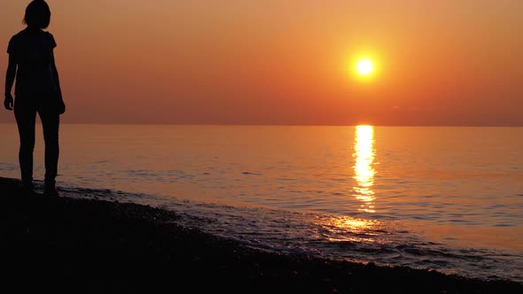 Silhouette of a Woman at Sunset Running Along the Seashore