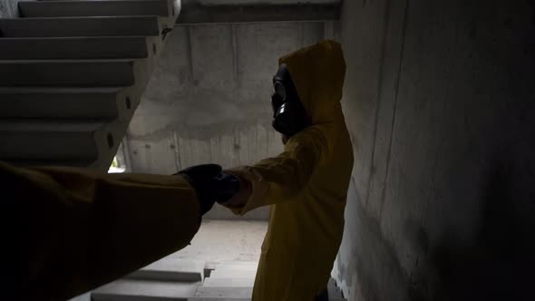 Woman in Gas Mask Gives Hand to Man to Follow Me Him in Abandoned Building on Stairs