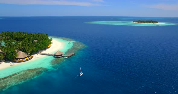 Aerial drone view of a man and woman sailing on a boat to a tropical island.