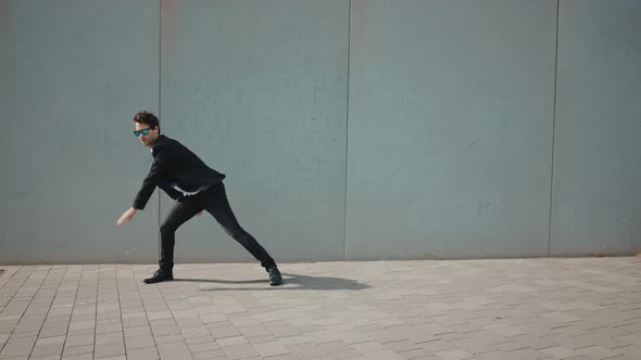 Flexible and cool businessman doing acrobatic tricks outdoor.