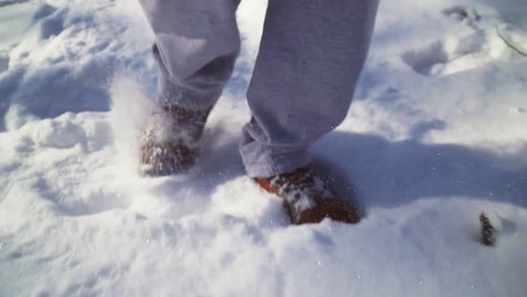 Close-up. Man walking on snow brown winter boots and gray sweatpants.