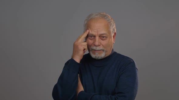 Aged Person Looks Straight and Moves Fingers on Temple