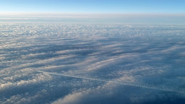 Incredible view from the cockpit of an airplane flying high above the clouds leaving a long white co