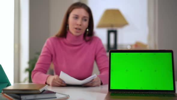 Chromakey Laptop with Blurred Young Freelancer Talking at Background Looking at Camera