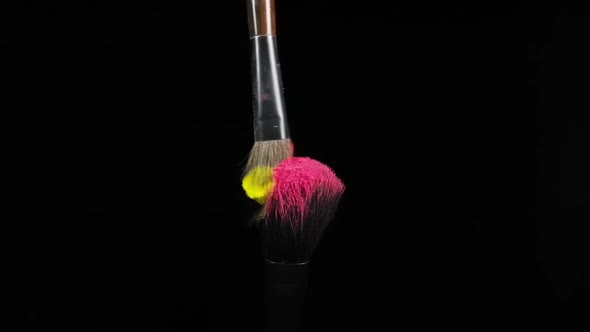 Makeup Brushes Touch Each Other on Black Dark Background and Small Particles of Color Cosmetics