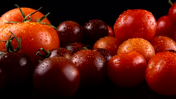 Cherry tomatoes on a black background in water drops.