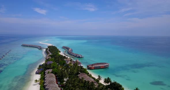 Wide birds eye island view of a white paradise beach and aqua blue ocean background in vibrant 4K