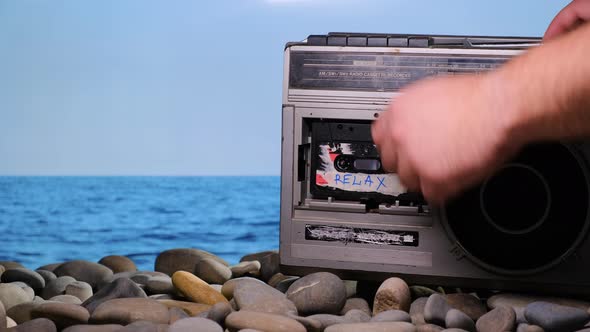 Vacationer Put on Stone Beach Old Vintage Retro Radio Tape Recorder and Puts on Audio Cassette with